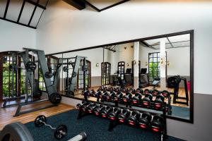 a gym with a large mirror and rows of equipment at Sanctuary Hotel Luang Prabang in Luang Prabang