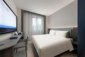 a hotel room with a large white bed and a desk at Shanghai Jiading Pingcheng Road Atour Light Hotel in Shanghai