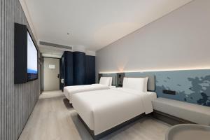 a hotel room with two beds and a tv at Shanghai Jiading Pingcheng Road Atour Light Hotel in Shanghai