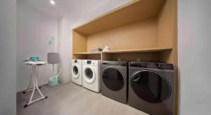 a laundry room with two washing machines and a table at 杭州火车东站钱唐嘉客酒店 in Wuhang