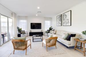 a living room with a white couch and chairs at Serenity on the Green in Sussex inlet