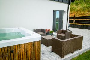 a bath tub sitting on a patio with chairs at KASZUBY - Domki na Szczycie - jeden na ogrodzonej działce z balia jacuzzi na wyłączność in Krzeszna