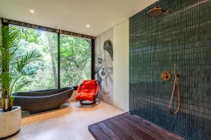 La salle de bains est pourvue d'une baignoire noire et d'une grande fenêtre. dans l'établissement Yara Wellness, à Munggu