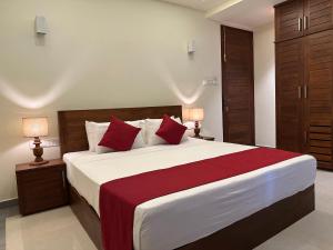 Un dormitorio con una cama grande con almohadas rojas. en Fortwill City Hotel, en Galle
