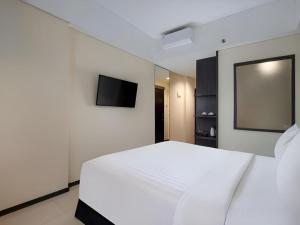 a bedroom with a white bed and a flat screen tv at Fashion Hotel Legian in Legian