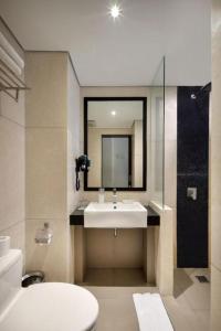 a bathroom with a sink and a mirror and a toilet at Fashion Hotel Legian in Legian