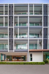 - une vue extérieure sur un bâtiment avec des tables et des chaises dans l'établissement Fourium Pattaya Hotel and Serviced Residence, à Ban Nong Chaeng