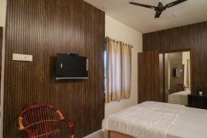 a bedroom with a bed and a tv on a wall at The Whistling Pine Woods in Varagampadi