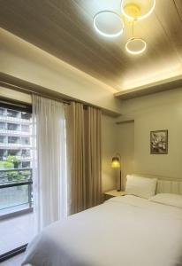 a bedroom with a white bed and a window at 2-BR Condo near Major Tourist Spots in Baguio in Sampong