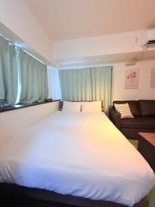 a large white bed in a room with a couch at Ruis Hakata in Fukuoka