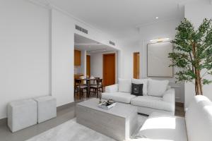 a living room with white furniture and a table at Maison Privee - City Heights Retreat with Panoramic Skyline Views in Dubai