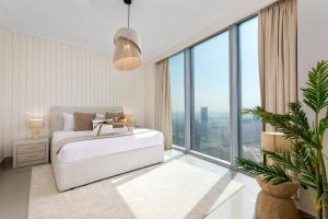 a white bedroom with a bed and large windows at Maison Privee - City Heights Retreat with Panoramic Skyline Views in Dubai
