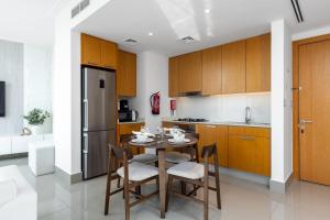 a kitchen with a table and chairs and a refrigerator at Maison Privee - City Heights Retreat with Panoramic Skyline Views in Dubai