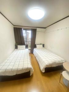 two beds in a room with a large window at Poppy ikebukuro in Wada