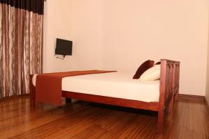 a bedroom with a wooden bed with a tv on the wall at Athithi Inn Homestay in Vaduvanchal