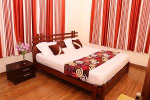 a bed in a bedroom with red curtains at Athithi Inn Homestay in Vaduvanchal