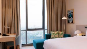 a hotel room with a bed and a chair and a window at Crowne Plaza Dushanbe by IHG in Dushanbe