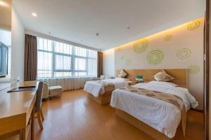 a hotel room with two beds and a desk at GreenTree Inn Nantong University Industrial Expo City Express Hotel in Dexingzhen +257 photos
