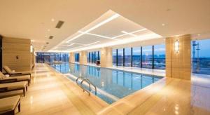 CaoshiにあるThe QUBE Hotel Jingzhouの大きな建物内の大きなスイミングプール