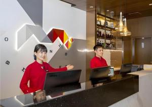 two people standing at a counter with their computers at Borrman Hotel Nanning Railway Station in Nanning