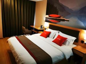 une chambre d'hôtel avec un grand lit avec des oreillers rouges dans l'établissement Thank Inn Hotel Hebei Langfang Xianghe County Guidu Furniture Center, à Jinxinzhuang 143 autres photos