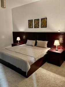 a bedroom with a large bed with two lamps on tables at شقق النخبه الجوهره1 in Arar
