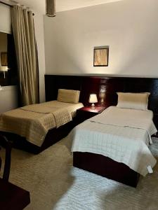 a bedroom with two beds and a table with a lamp at شقق النخبه الجوهره1 in Arar