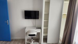 a white desk with a chair and a tv on a wall at 1 chambre meublé avec cuisine privé métro 7 la Courneuve in La Courneuve