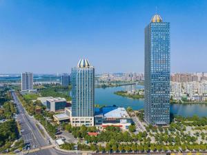 two tall buildings in a city next to a body of water at Eurasia Convention International Hotel in Wuhan