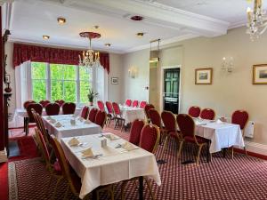 a dining room with tables and red chairs at The Hand Hotel Llangollen by Compass Hospitality in Llangollen