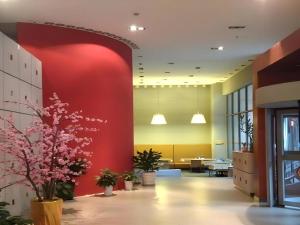 an office lobby with a red wall and flowers at Jinjiang Inn Hangzhou Xihu Avenue Branch in Hangzhou