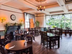 a restaurant with tables and chairs and a clock on the wall at The Hand Hotel Llangollen by Compass Hospitality in Llangollen