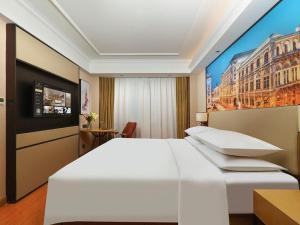 a bedroom with a white bed and a painting on the wall at Vienna Hotel Tianjin Guizhou Road Branch in Tianjin