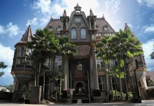 a large building with palm trees in front of it at Gajahmada Graha Hotel in Malang