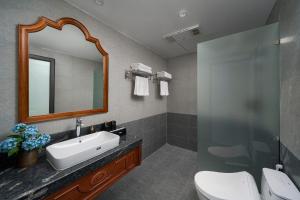 a bathroom with a sink and a mirror at Sơn Nữ Emerald Hill Hotel in Bak Kan