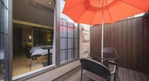a patio with a table and a red umbrella at Business Design Hotel LUV in Incheon