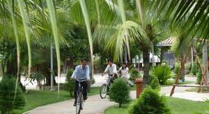 2 personnes à vélo dans un parc planté de palmiers dans l'établissement Can Gio Resort, à Ấp Long An