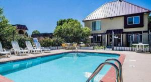 une piscine avec des chaises et une maison dans l'établissement Econo Lodge Urbandale - Northwest Des Moines, à Urbandale