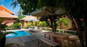 - une terrasse avec un banc et un parasol à côté de la piscine dans l'établissement Sambopich Chenla Hotel, à Phumĭ Achary Leăk