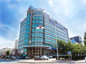 un grand bâtiment en verre avec un drapeau devant lui dans l'établissement Jinjiang Metropolo Hotel - Qingdao Chengyang District Government, à Qingdao