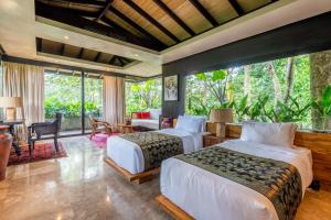 deux lits dans une chambre avec une grande fenêtre dans l'établissement Yara Wellness, à Munggu