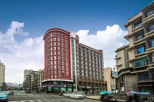 un edificio alto rojo en una calle de la ciudad con coches en Home Inn Guiyang Railway Station, en Guiyang