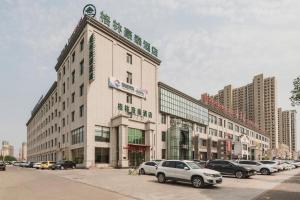 a large building with cars parked in a parking lot at GreenTree Inn Tangshan Xueyuan Road Business Hotel in Fujiatun