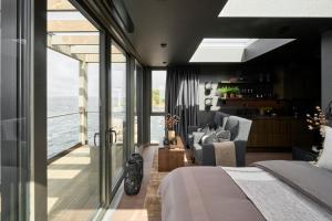 een slaapkamer met een bed en uitzicht op de oceaan bij Hideaway Herdla luxurious cabins 15 m above the sea in Herlø