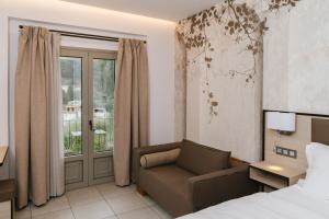 a bedroom with a bed and a chair and a window at Trofonios Boutique Hotel in Levádeia