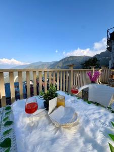 a table with two glasses of wine on a balcony at Hotel Mini Switzerland In Dalhousie in Dalhousie