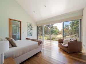 WilyabrupにあるHundred Acre Woodland Retreatのベッドルーム1室(ベッド1台、椅子、窓付)