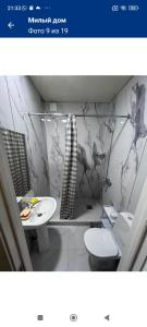 a white bathroom with a toilet and a sink at Гостевой дом in Tokmok