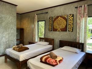 a bedroom with two beds with towels on them at บ้านสราญรัตน์ in Ban On Luai