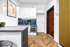 une cuisine avec des armoires blanches et un plancher en bois dans l'établissement EASY RENT Apartments - Chopina 32, Centrum, 24h Check-in, à Lublin